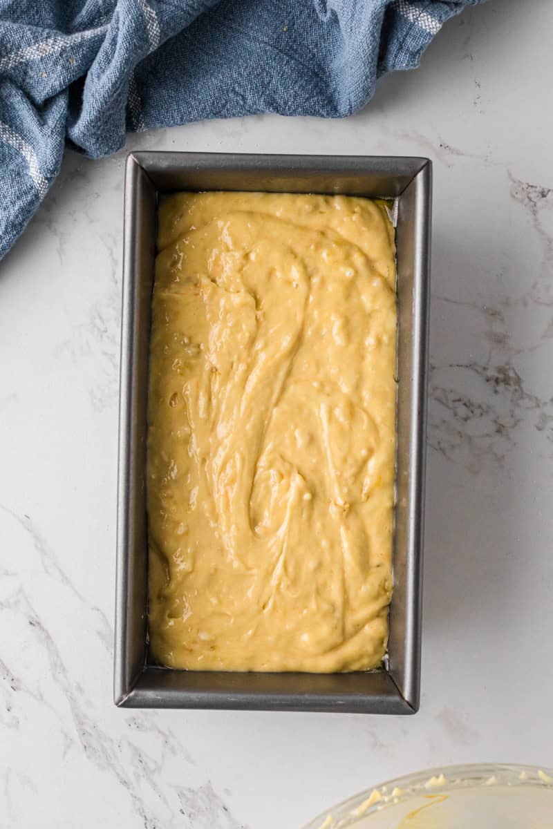 pouring the banana bread batter into a bread pan.