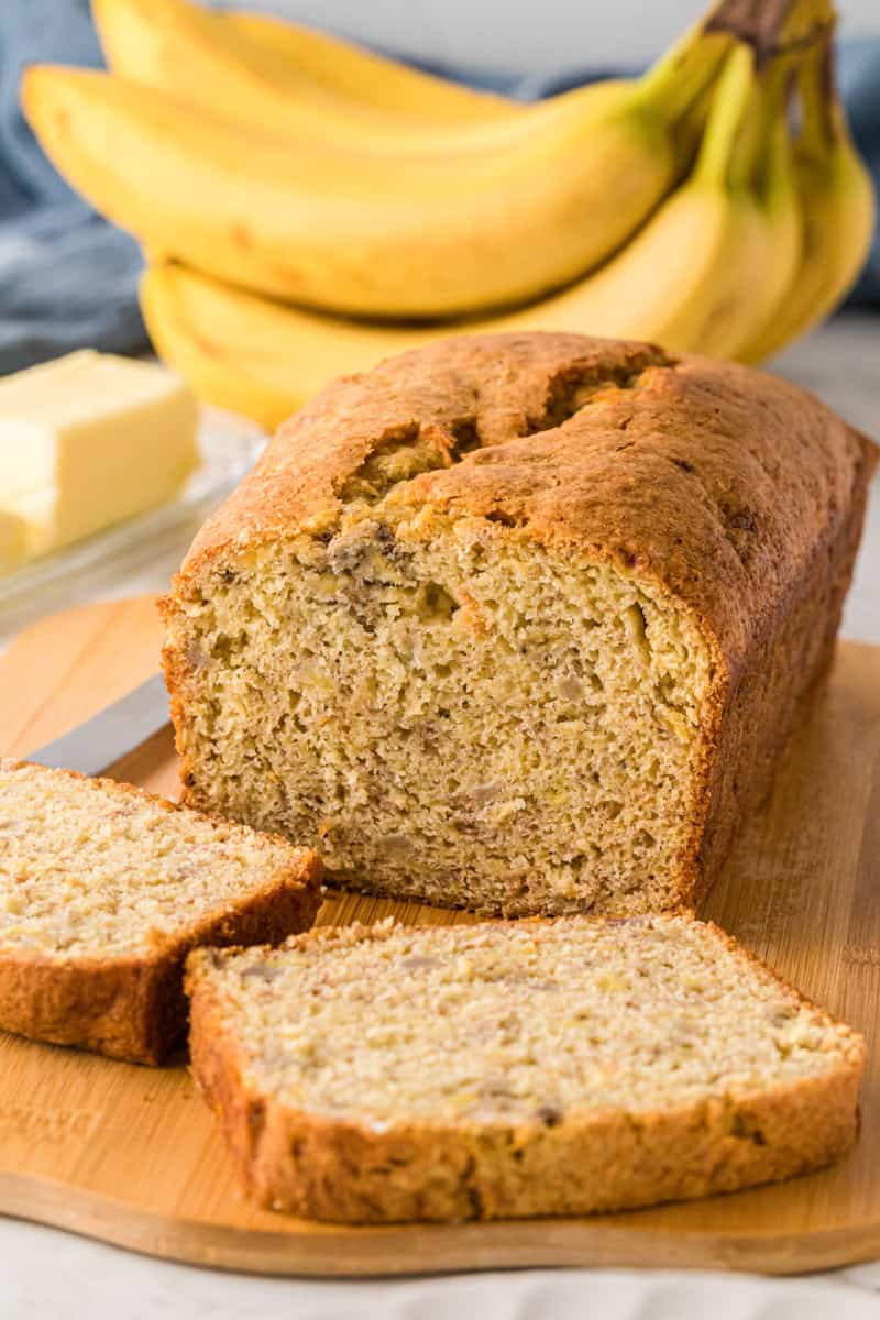 Banana Bread Loaf sliced on wooden cutting board.