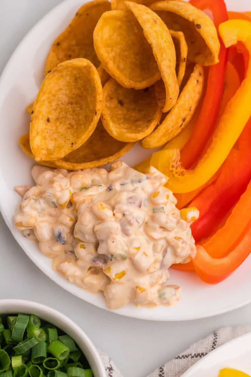 a serving of the dip on a plate with peppers and chips.