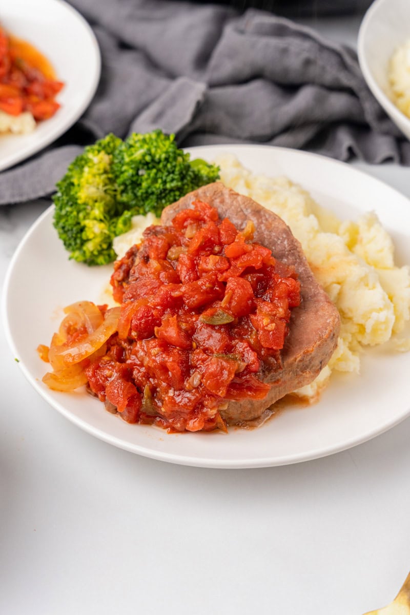 Slow Cooker Swiss Steak served on a white plate with mashed potatoes.