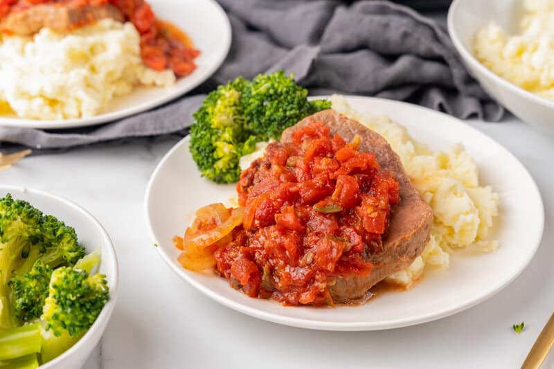 closeup of the Swiss Steak served on a white plate with mashed potatoes.