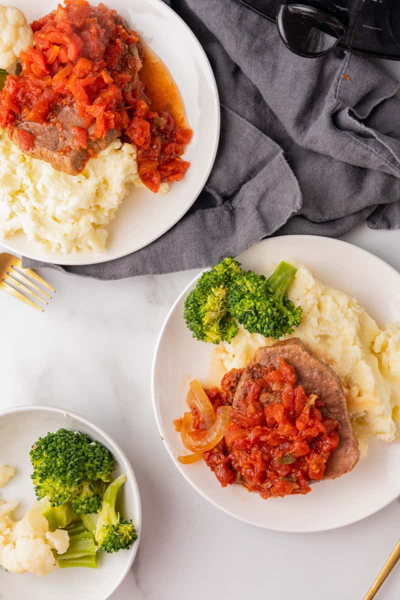 top-down view of two plates of the Swiss Steak dinner.