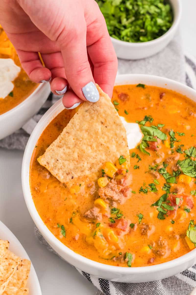 dipping a tortilla chip into the Beef Nacho Soup.