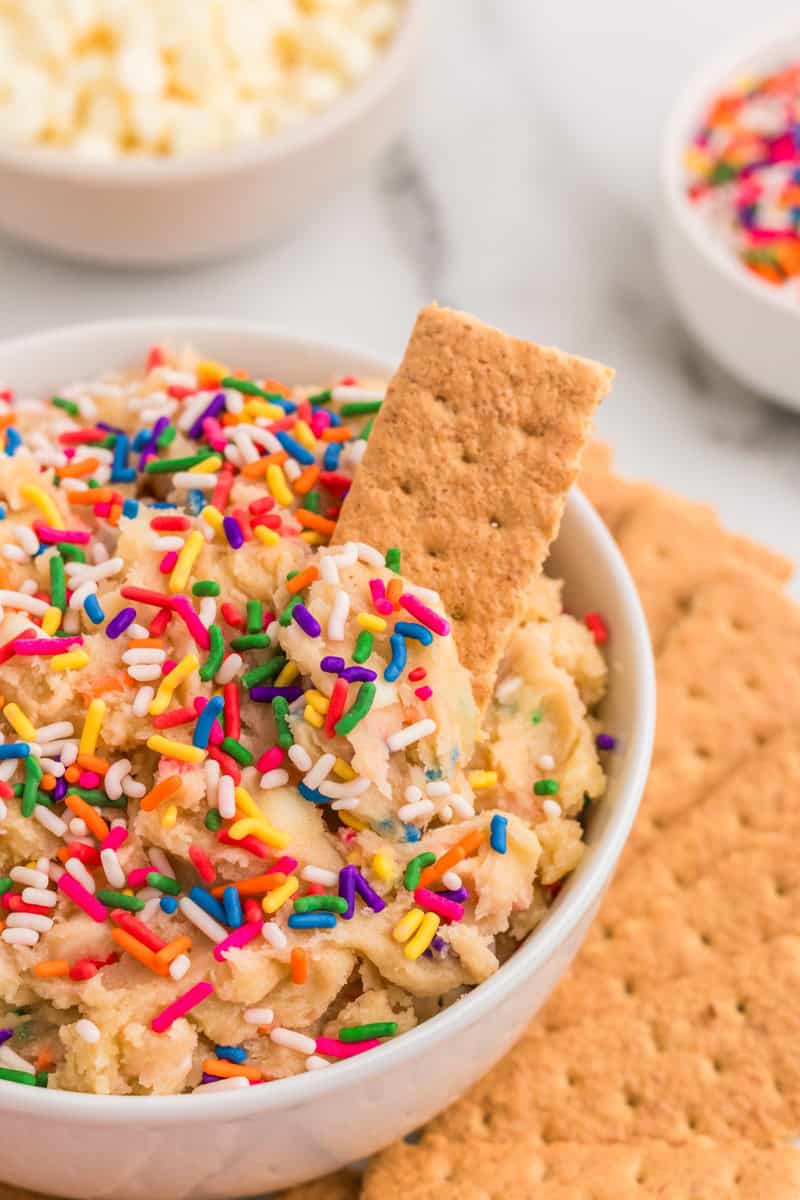 dipping a graham cracker into the Edible Cake Batter.