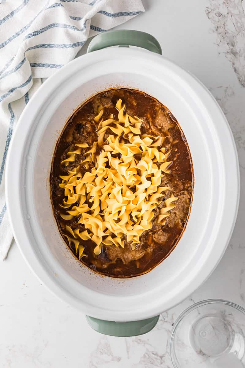 adding the egg noodles to the slow cooker.