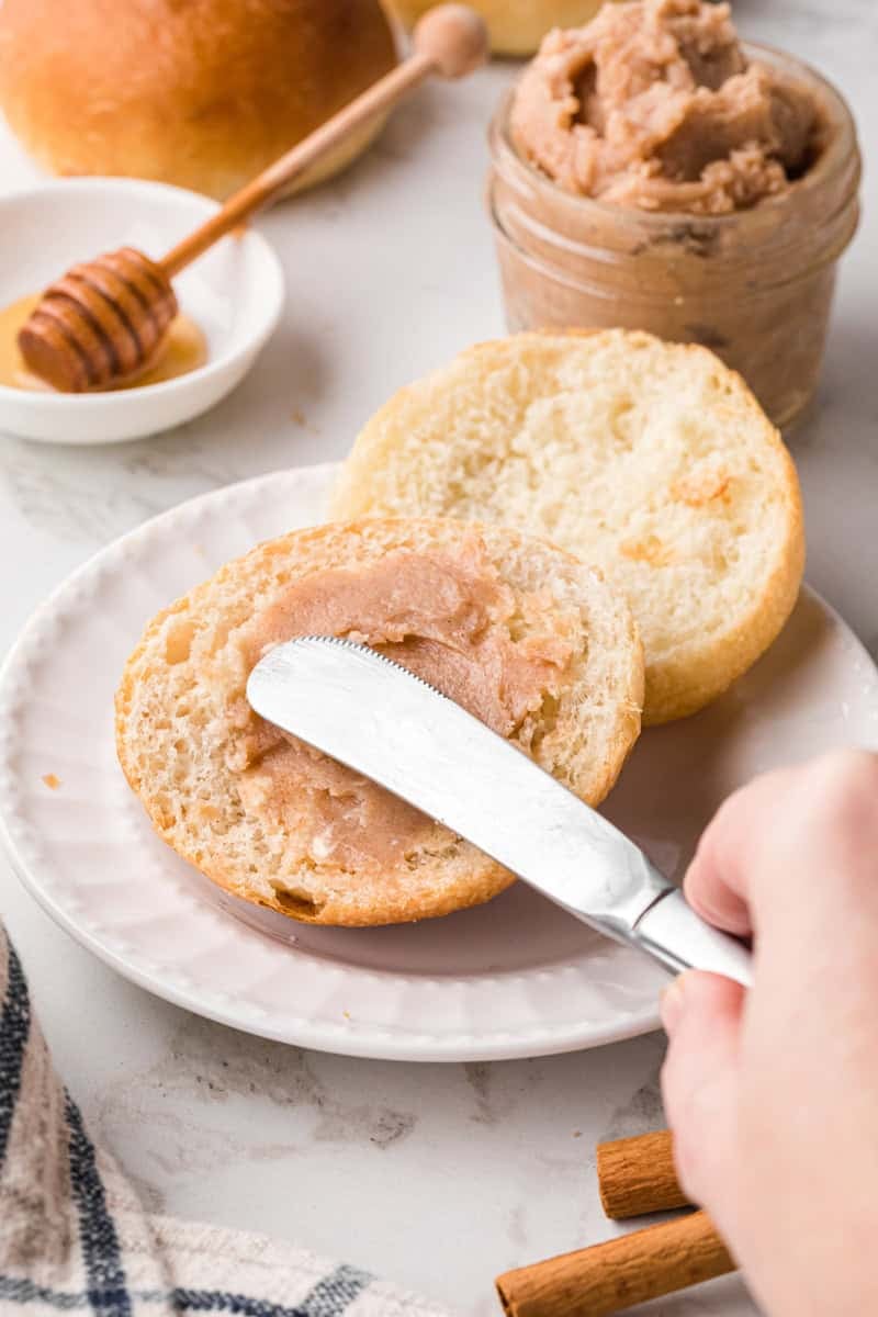 spreading the honey butter on a roll.
