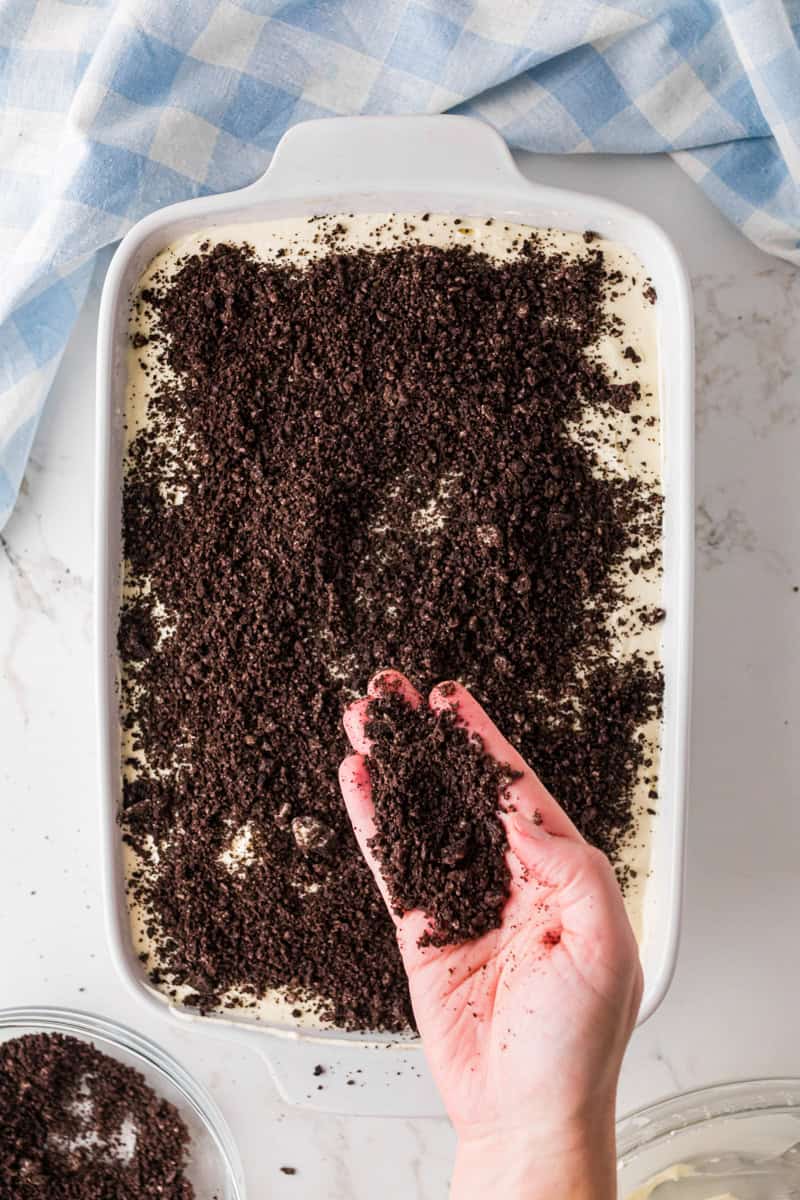 sprinkling more crushed Oreos on top over the cake.