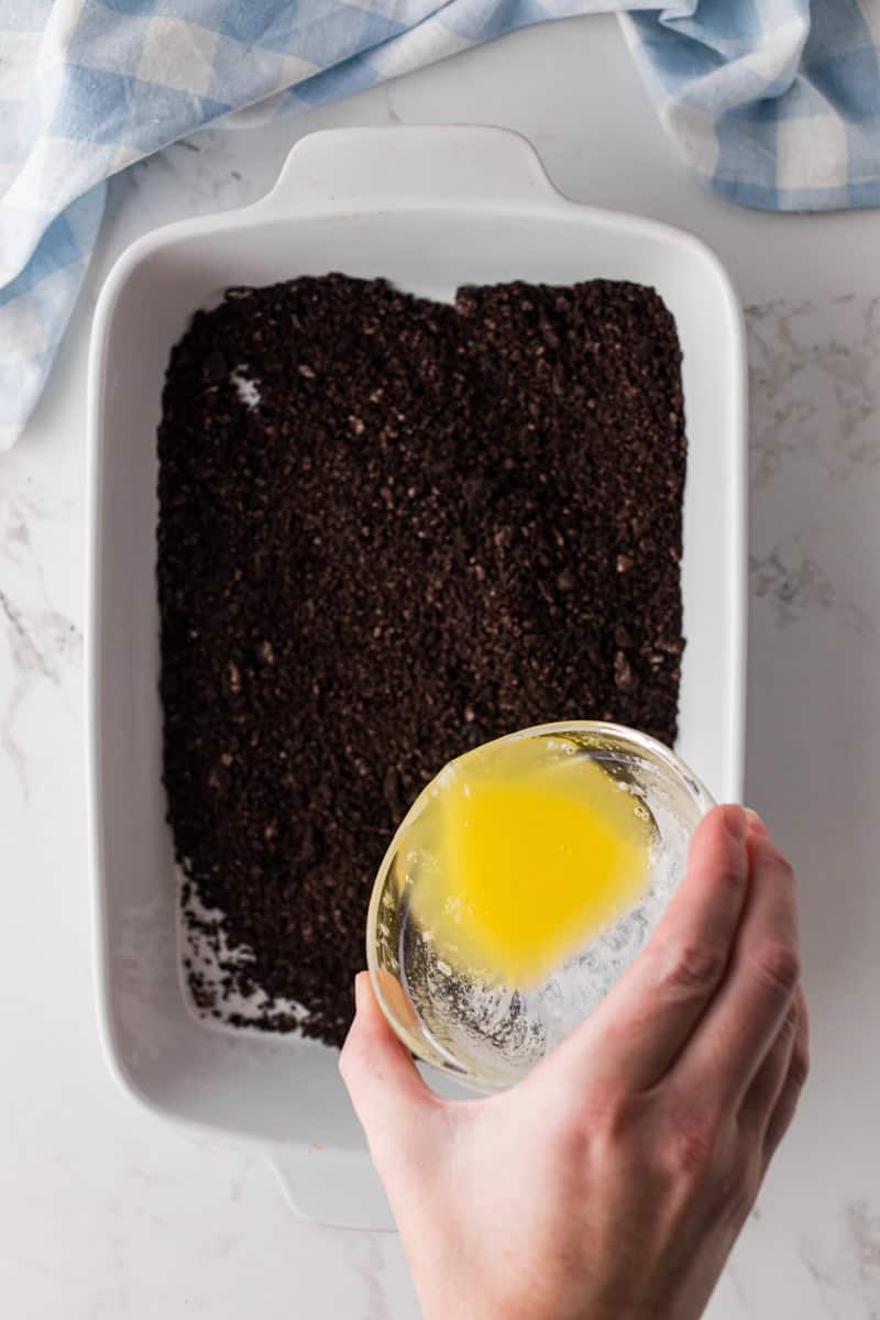 pouring butter over crushed Oreos to make the crust.