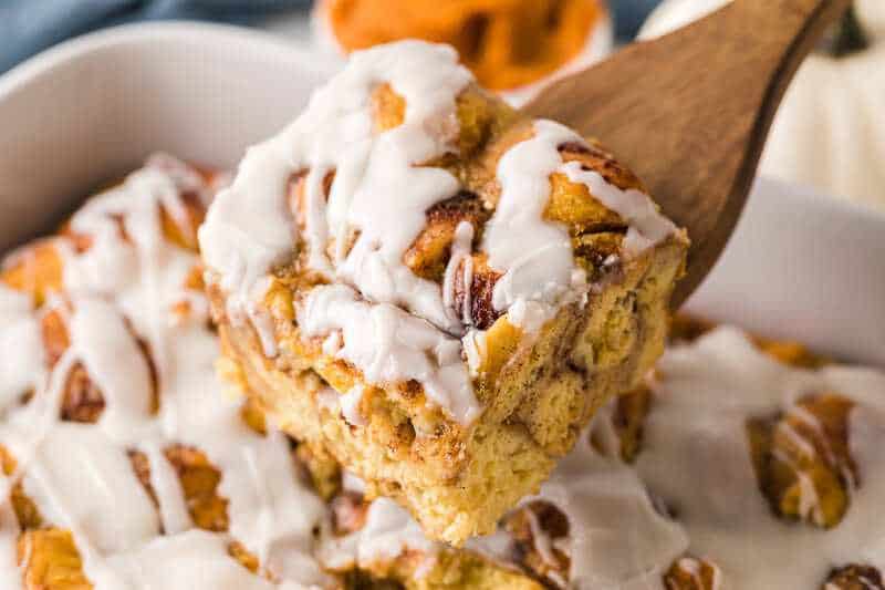 serving a slice of the Cinnamon Roll Casserole on a wooden spatula.