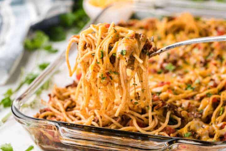 Taco Spaghetti being served out of a glass casserole dish.
