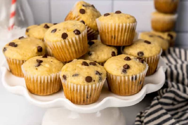 Mini Banana Chocolate Chip Muffins stacked on a white serving tray.