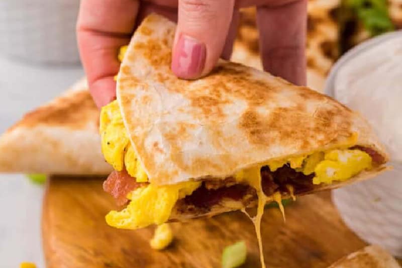 Breakfast Quesadilla slice in hand.