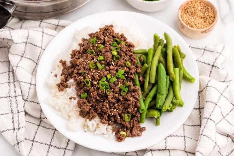 Asian Ground Beef served on a bed of rice with green beans.