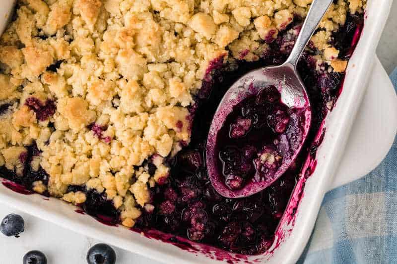 Blueberry Cobbler being served out of a white baking dish.