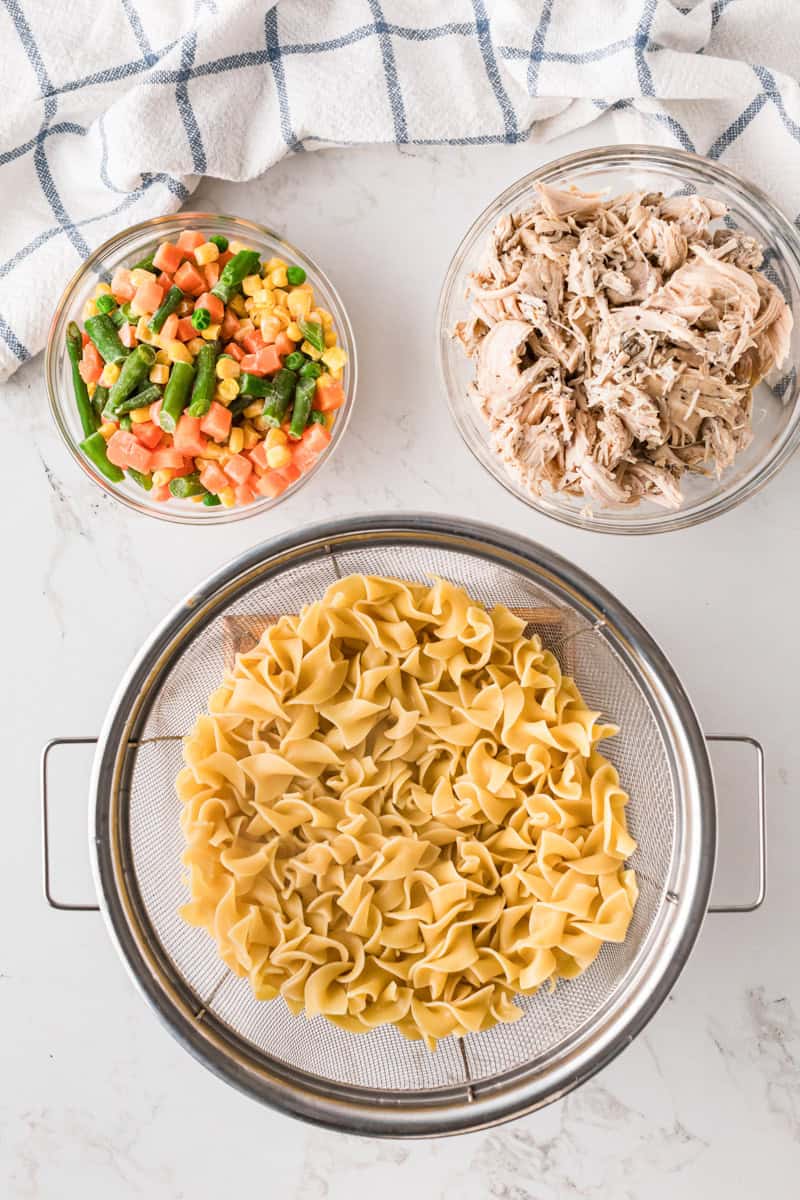 noodles, chicken and veggies in separate bowls before being mixed.