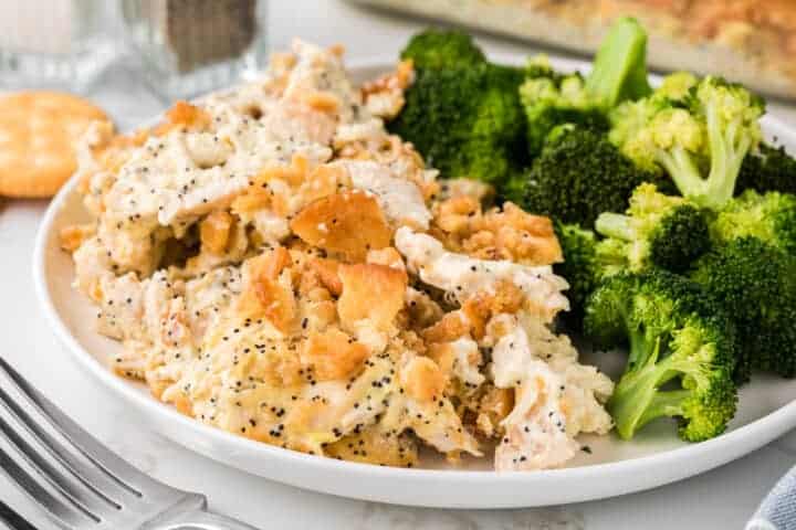 Poppy Seed Chicken Salad casserole served with broccoli on a white plate.