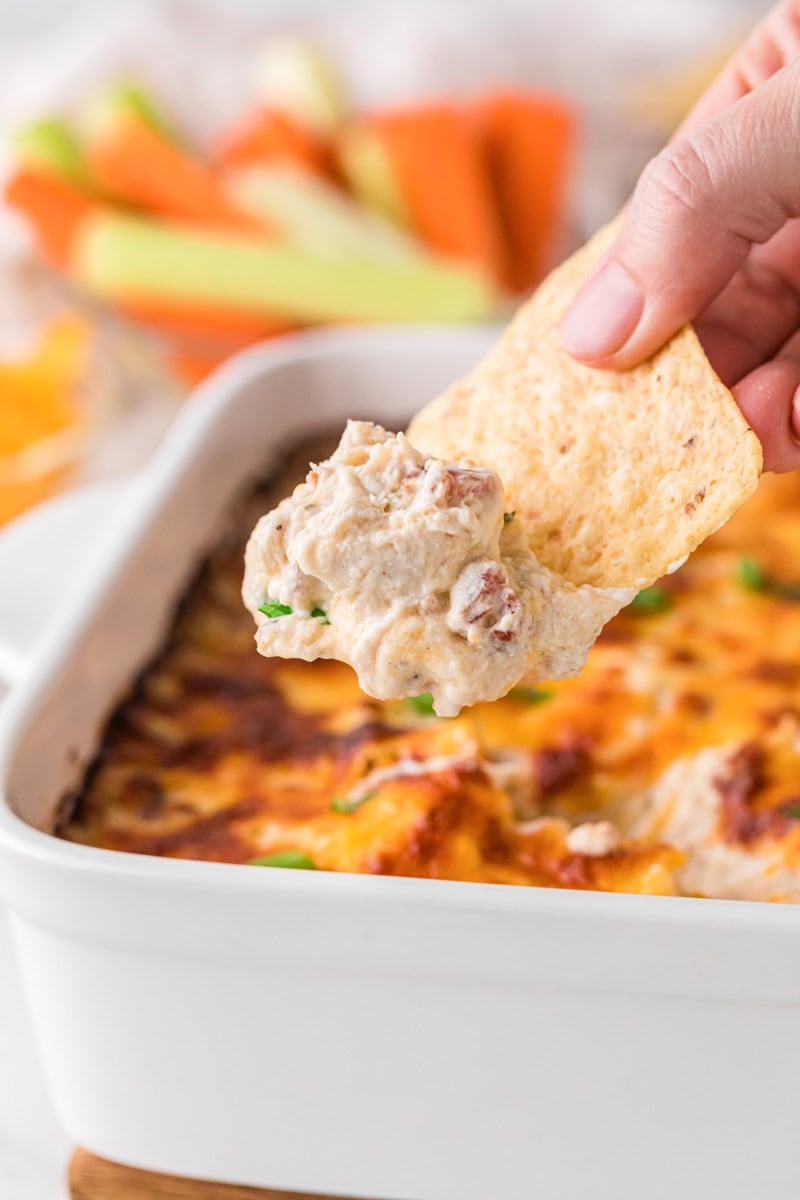 dipping a tortilla chip into the Crack Chicken Dip.