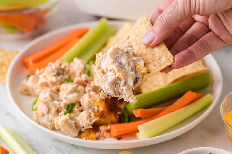 dipping a tortilla chip into the Crack Chicken Dip.