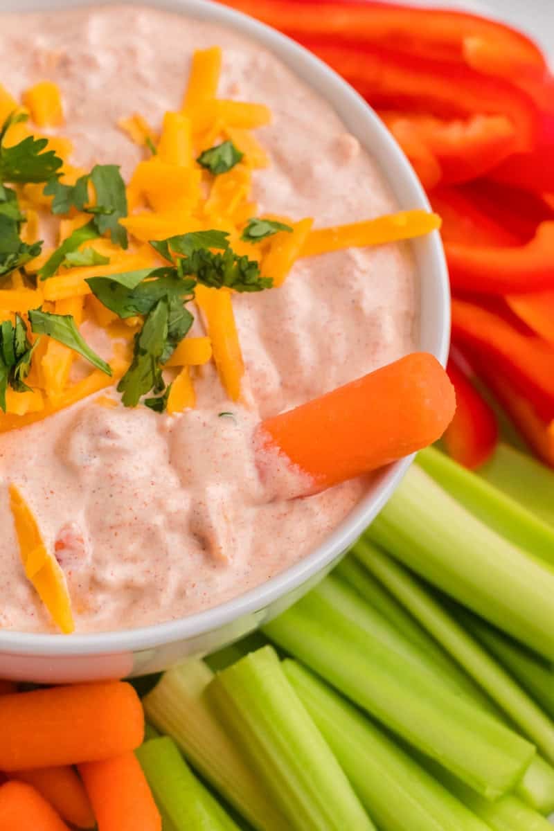 dipping a carrot into the Fiesta Taco Dip.