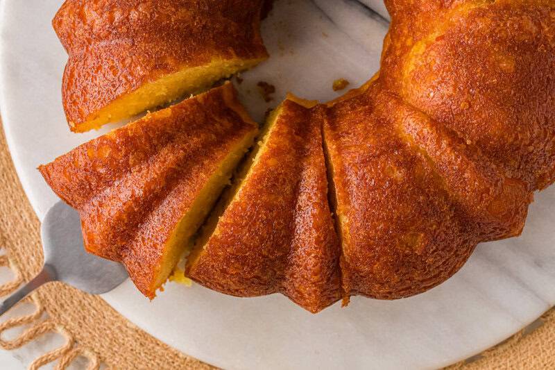 top-down view of the Orange Juice Cake being sliced on serving tray.