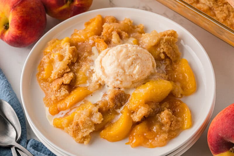 Peach Cobbler served with ice cream on a white plate.