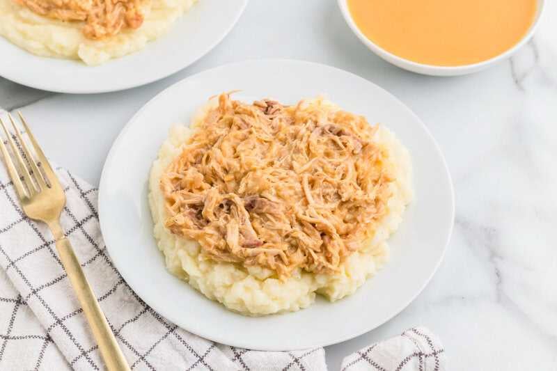 Slow Cooker Chicken and Gravy served on a bed of mashed potatoes.