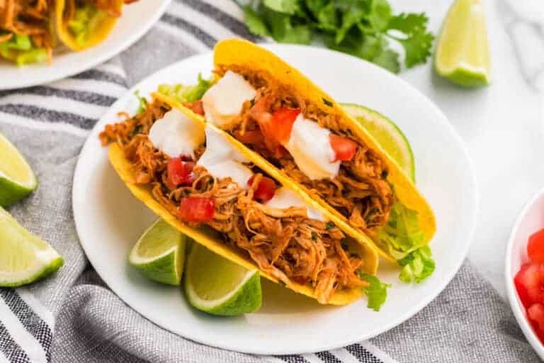 Two Slow Cooker Cilantro Lime Chicken Tacos served on a white plate.