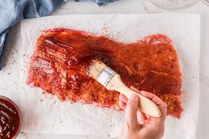 brushing the seasoned ribs with the BBQ Sauce.
