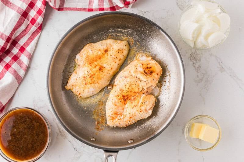 cooking the chicken in the skillet.