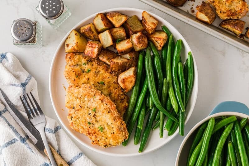 sheet pan pork chops and potatoes served with green beans.