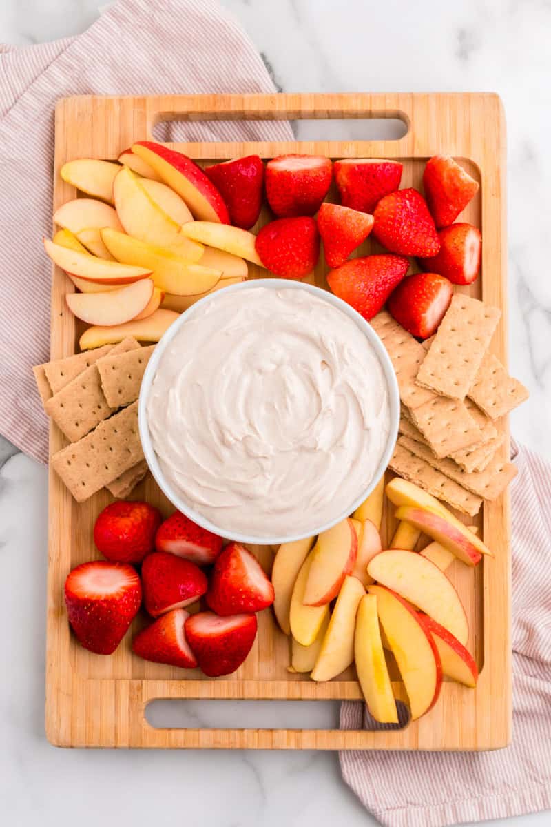Snickerdoodle Dip on a wooden serving tray with fruit and graham crackers.