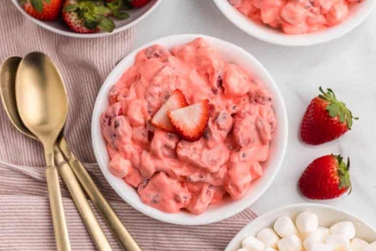 Creamy strawberry fluff salad topped with fresh strawberries.
