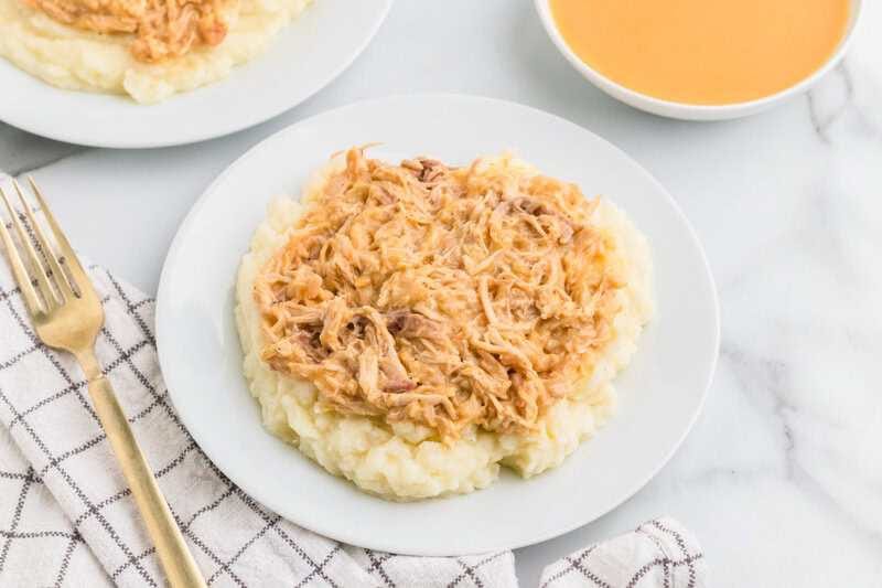Slow Cooker Chicken and Gravy served on a bed of mashed potatoes.