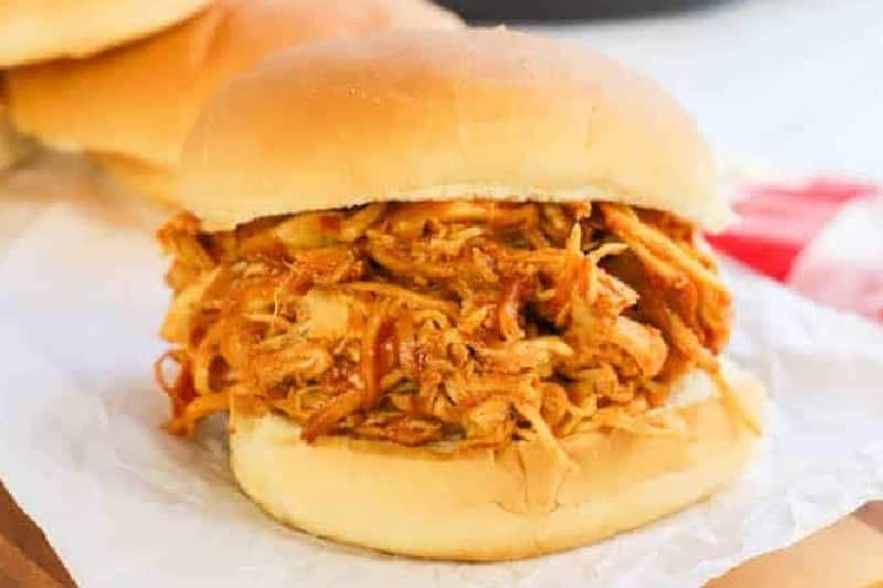 Slow Cooker BBQ Chicken sandwich on parchment paper.