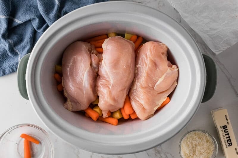 The Chicken in the slow cooker on top of the potatoes and carrots.