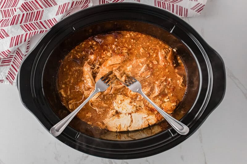 shredding the chicken in the slow cooker with two forks.