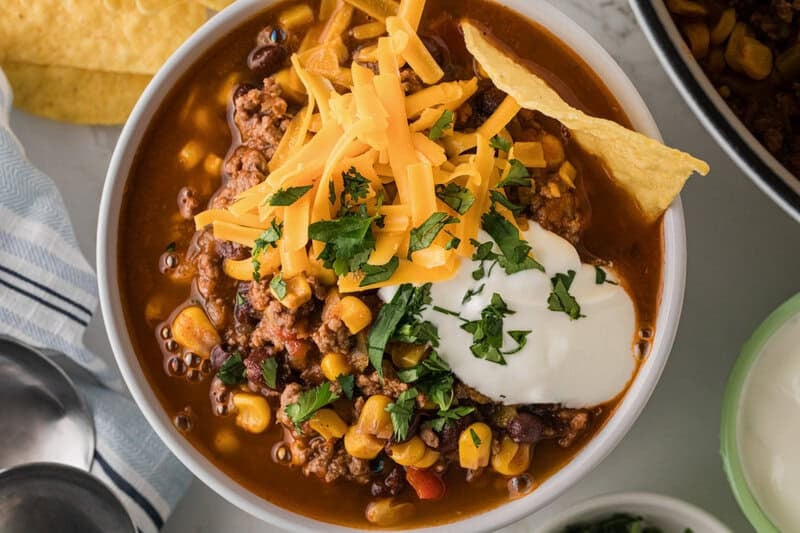 top-down view of the taco soup served in a white bowl.