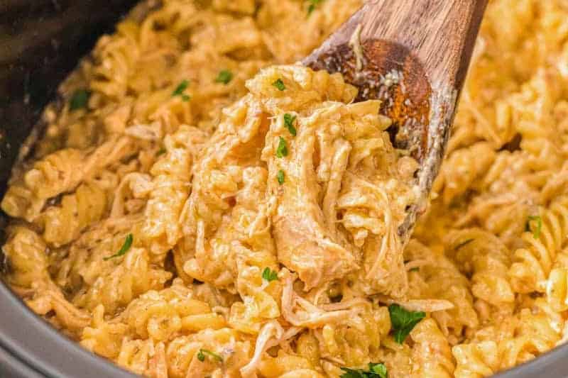 closeup of the slow cooker Italian Chicken Pasta being served with a wooden spoon.