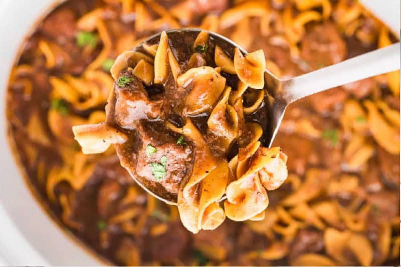 serving the Slow Cooker Beef and Noodles with a ladle.