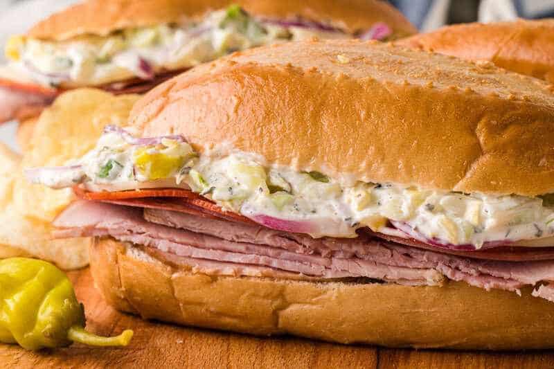 closeup of two Grinder Sandwiches on a wooden board with chips.