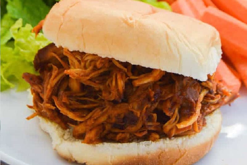 Slow Cooker Root Beer Chicken sandwich served on a white plate.