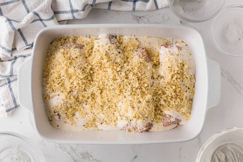 adding the breadcrumbs on top of the chicken in the baking dish.