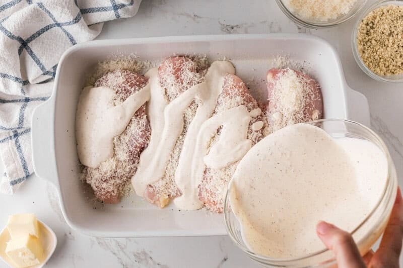 pouring the Caesar Dressing over the chicken breasts.