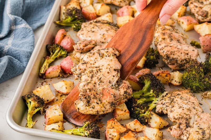 serving the Sheet Pan Chicken with a wooden spatula.