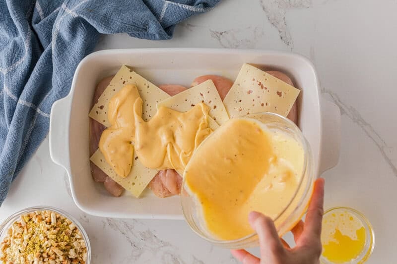 pouring the soup mixture over the chicken and Swiss Cheese.