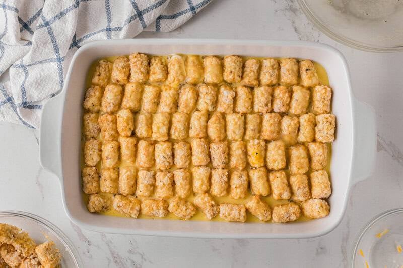 placing the tater tots on top of the sausage then the egg mixture poured on top.