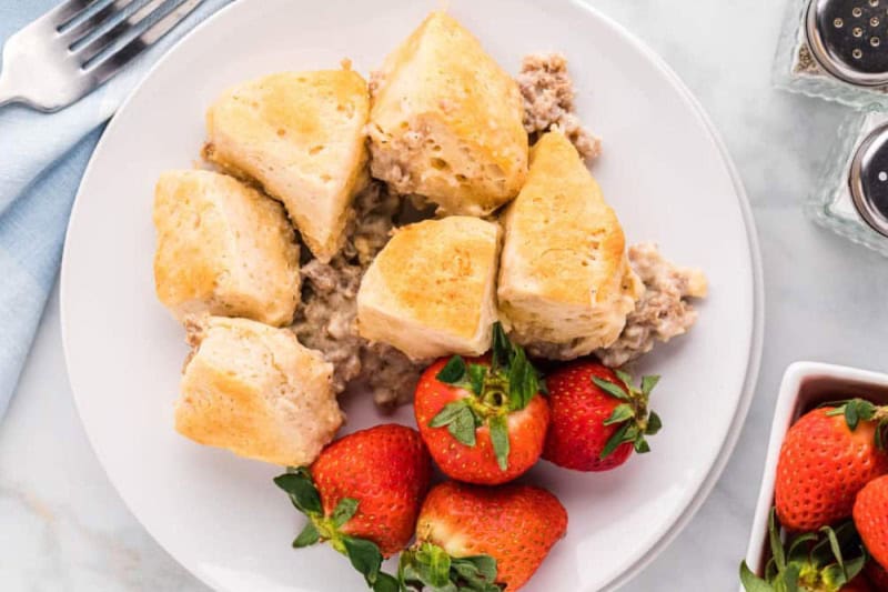 Biscuits and Gravy served on a white plate with strawberries.