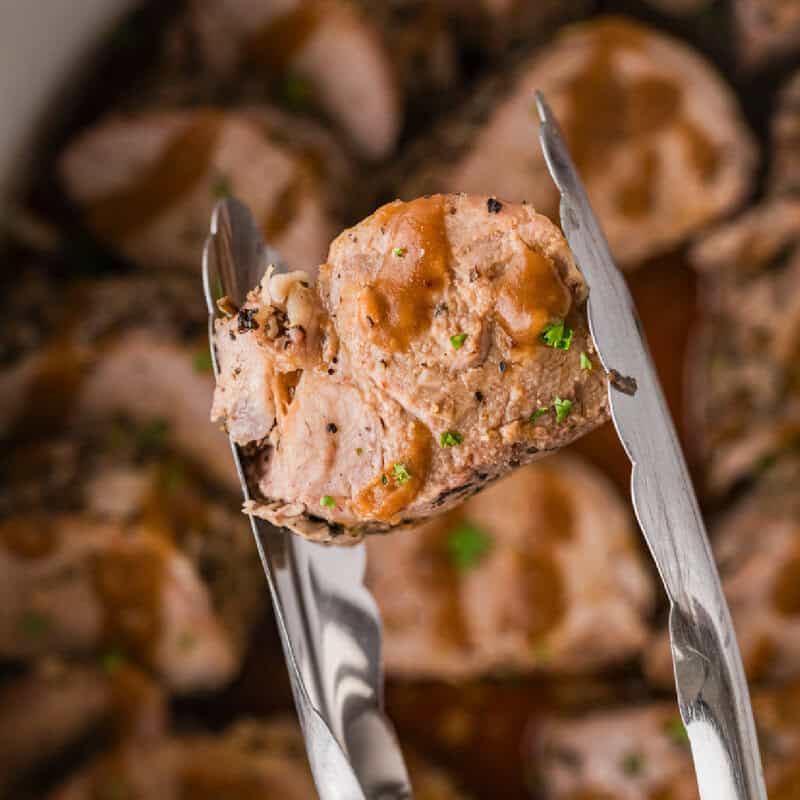 serving a slice of the pork loin with tongs.