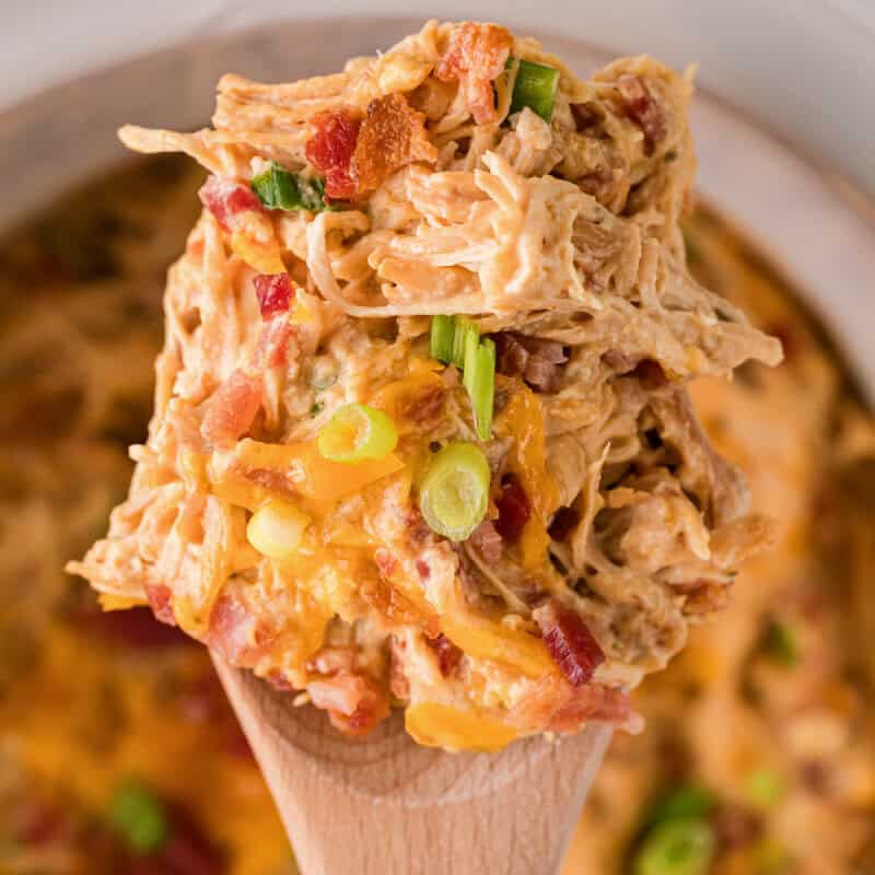 closeup of serving the Crack Chicken on a wooden spoon.
