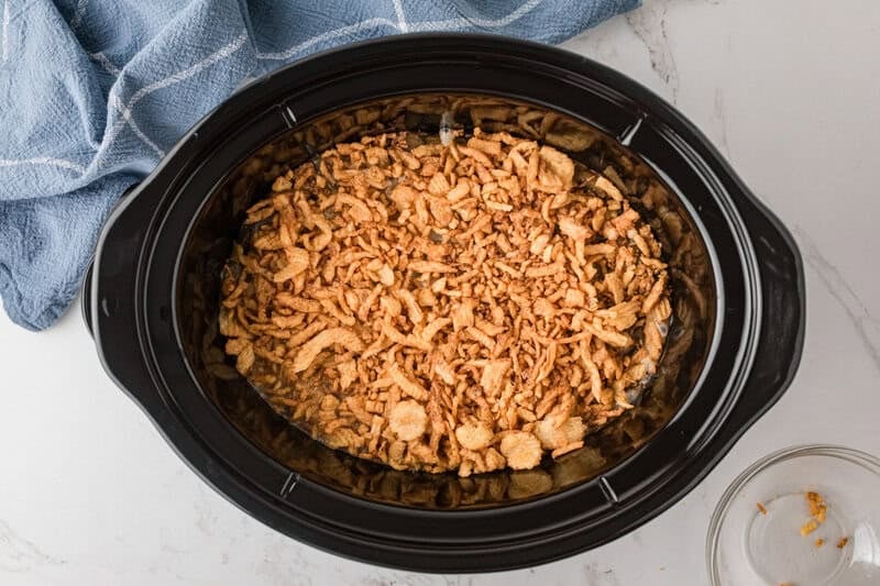 adding the French Fried Onions on top of the casserole in the slow cooker.